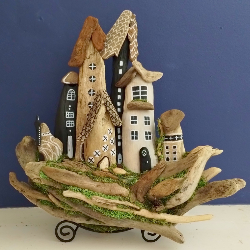 Decorative arrangement of small houses made from driftwood and other natural materials against a blue background.