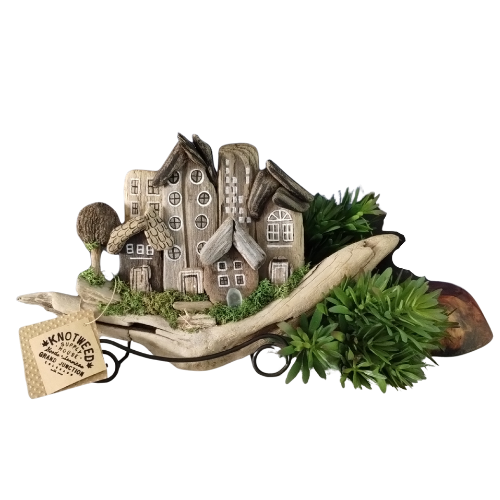 Decorative scene with miniature driftwood houses on a branch with greenery