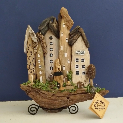 Decorative driftwood houses on a stand with a blue background