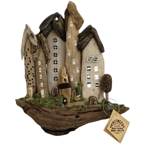 Decorative driftwood village sculpture with a tag on a white background