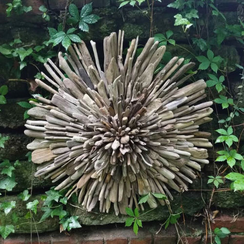 Driftwood art piece shaped like a starburst against a natural background with green leaves.